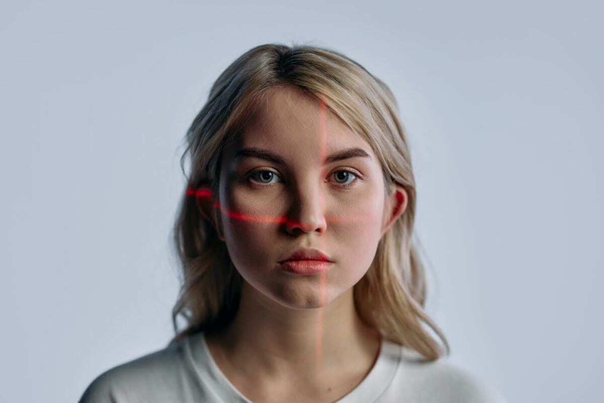 A woman looks into the camera, a red crosshair scanning her is on her face.