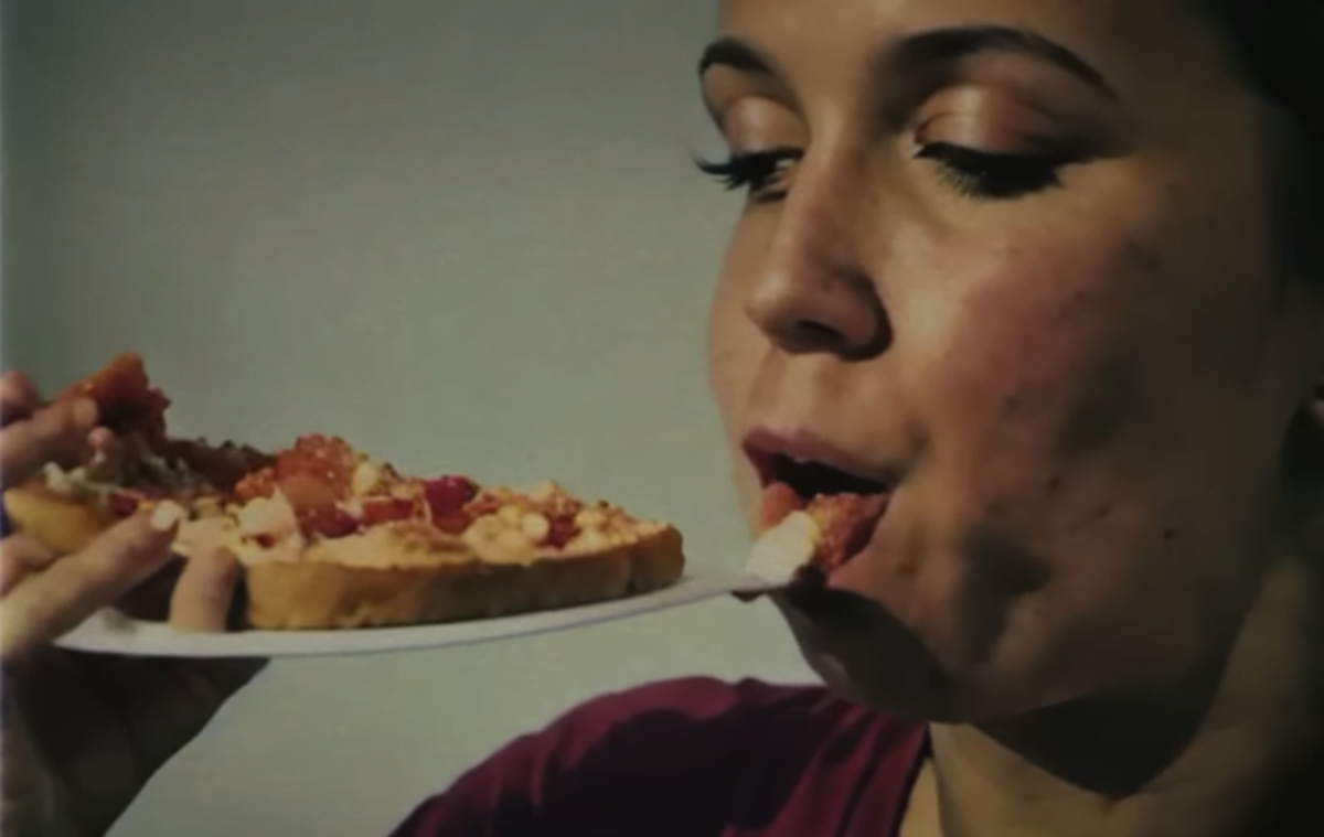A woman eats the plate on which there is a pizza. The scene is generated with AI.