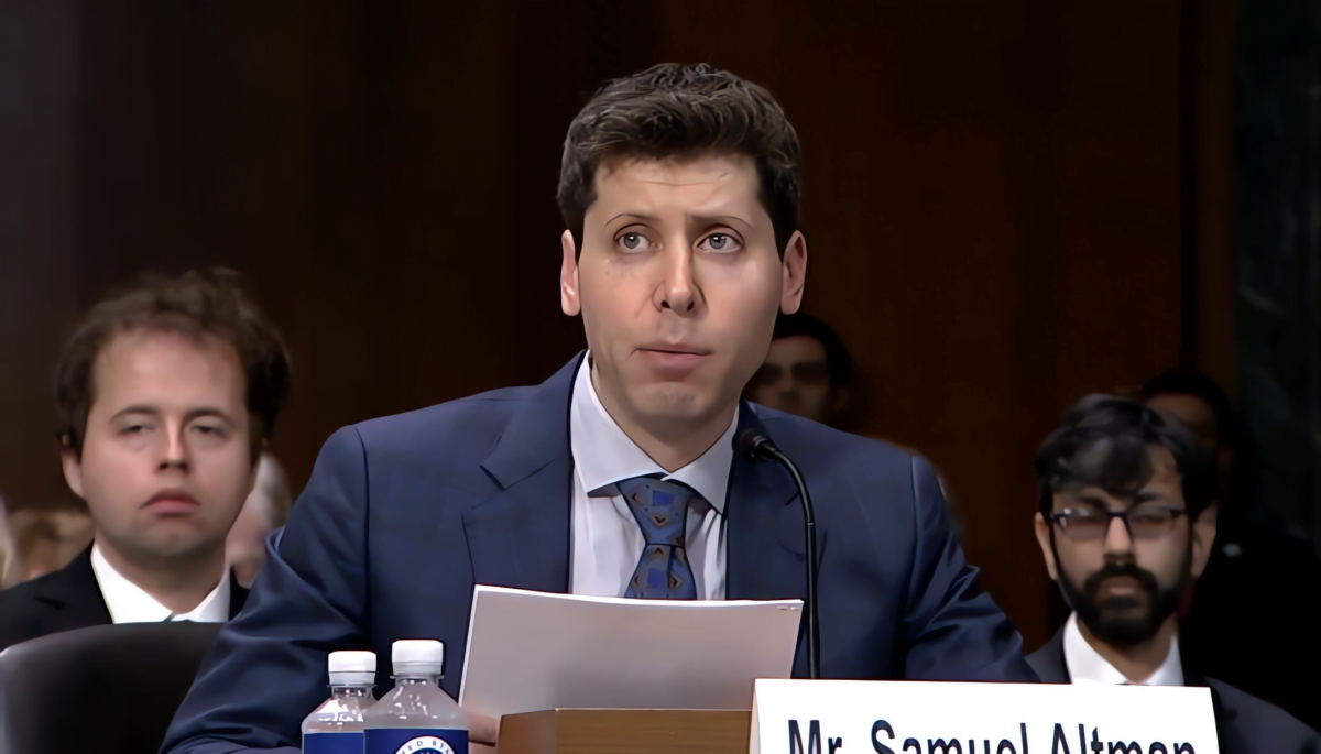 OpenAI CEO Sam Altman sits at a desk in the Senate and reads a statement from papers in front of him.