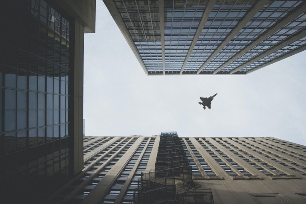 A fighter jet flies over skyscrapers